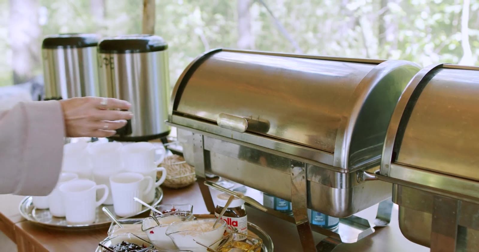 Coffee urns beside chafing dishes at a buffet